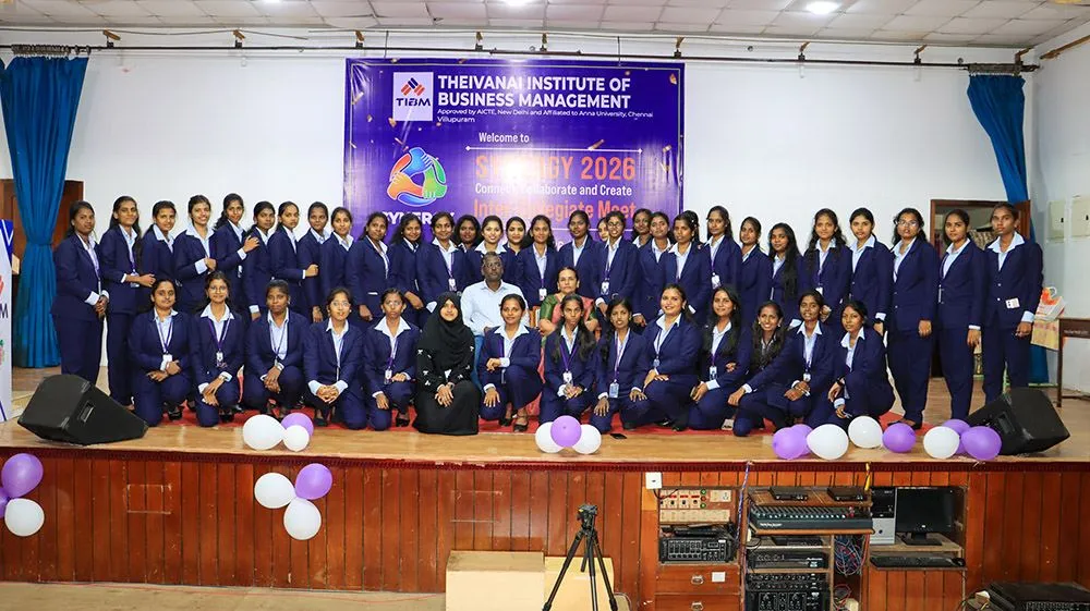 TIBM MBA students in navy blazers on stage with their guests, in front of the SYNERGY 2026 banner